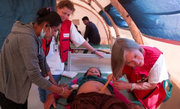 En Røde Kors sykepleier lytter med stetoskop på en kvinnes mage