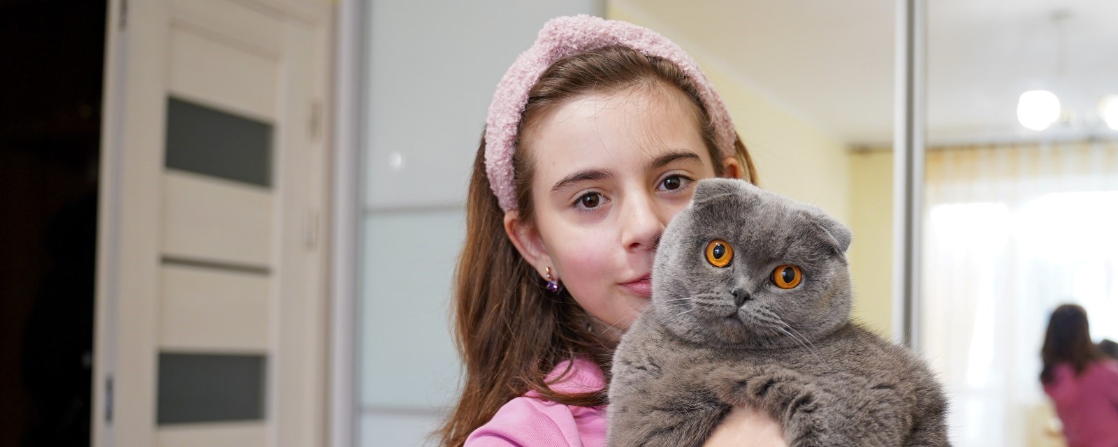 Jente holder en katt med gule øyne i armene