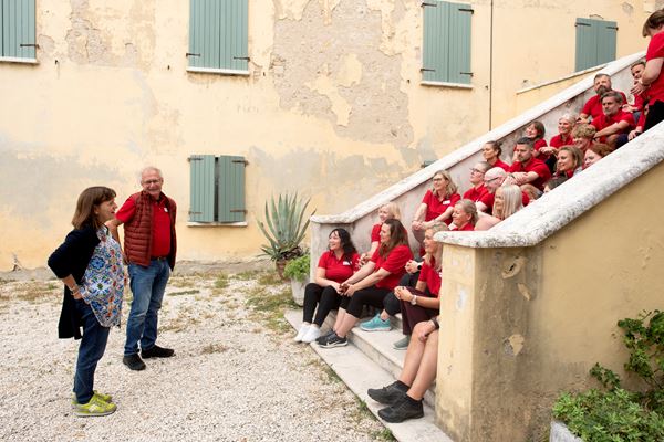 To guider står foran en gruppe mennesker som sitter i en trapp i en gammel italiensk gårdsplass