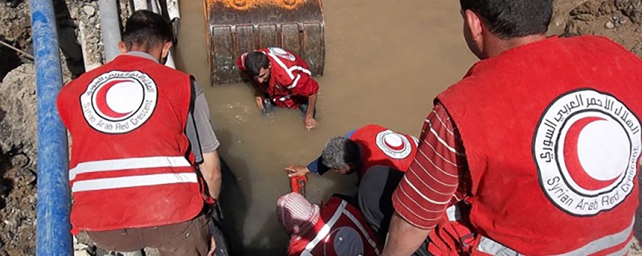 Vanningeniører med ikledd Røde Halvmåne emblemer jobber med å reparere vannrør i byen Dier Ezzor. 