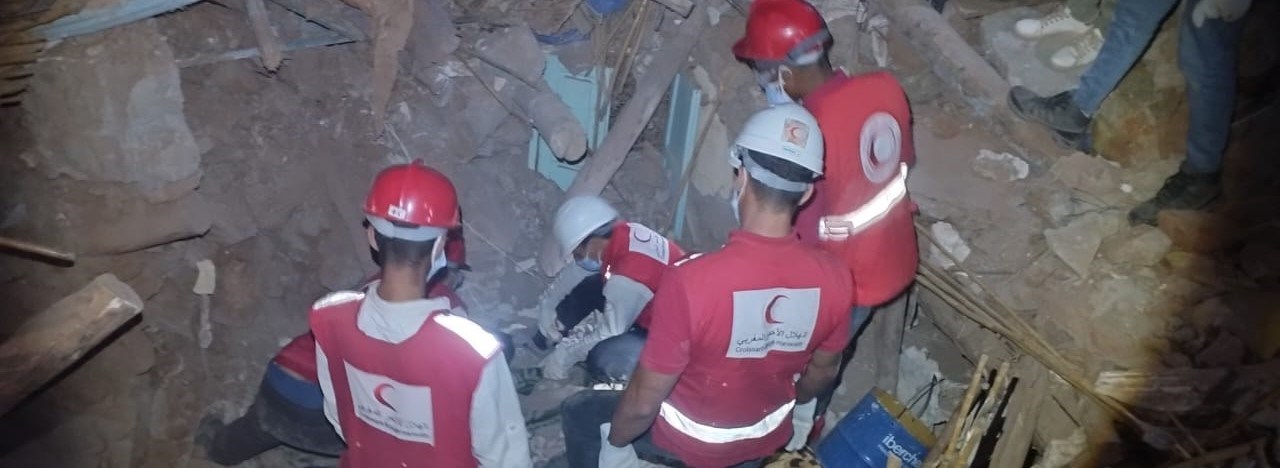 Fire redningsarbeidere fra Røde Kors graver i ruiner