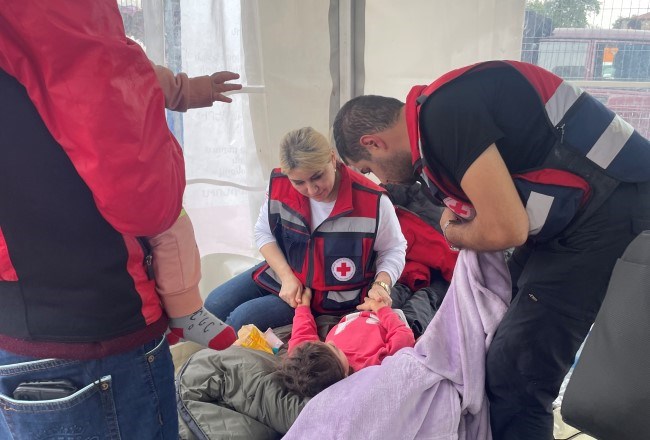 Røde Kors hjelper en mor og et barn som ligger på en feltseng