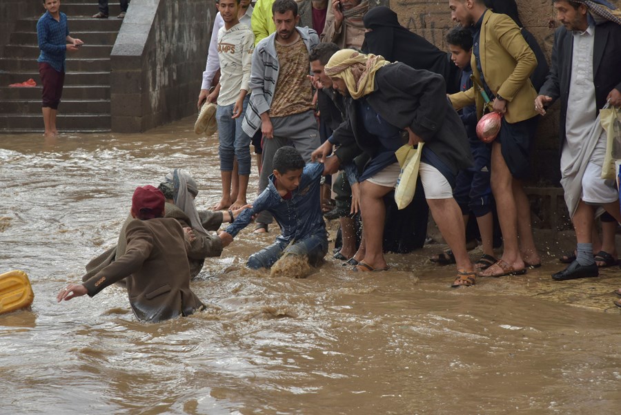 En gutt får hjelp til å komme seg ut av vannmassene etter en flom i Jemens hovedstad Sanaa.