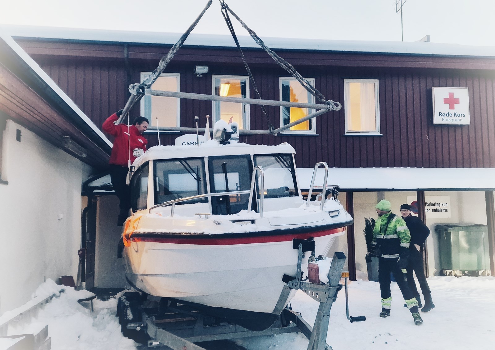 En båt heises opp i kran utenfor et Røde Kors-huset i Porsgrunn.