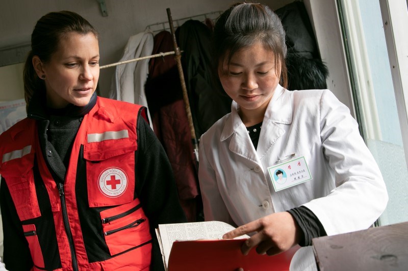 En kvinne i Røde Kors uniform snakker med en kvinne ikledd hvit legefrakk.