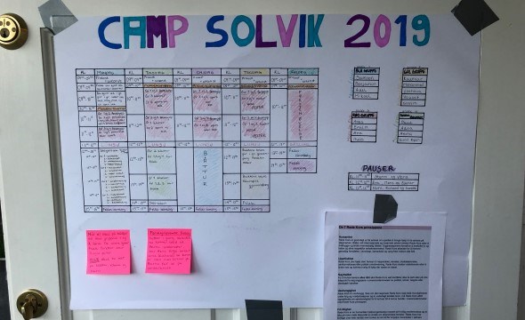 Oversikt over timeplan på camp Solvik 2019 som henger på en dør. Også oversikt over de fire forksjellige gruppene på campen.