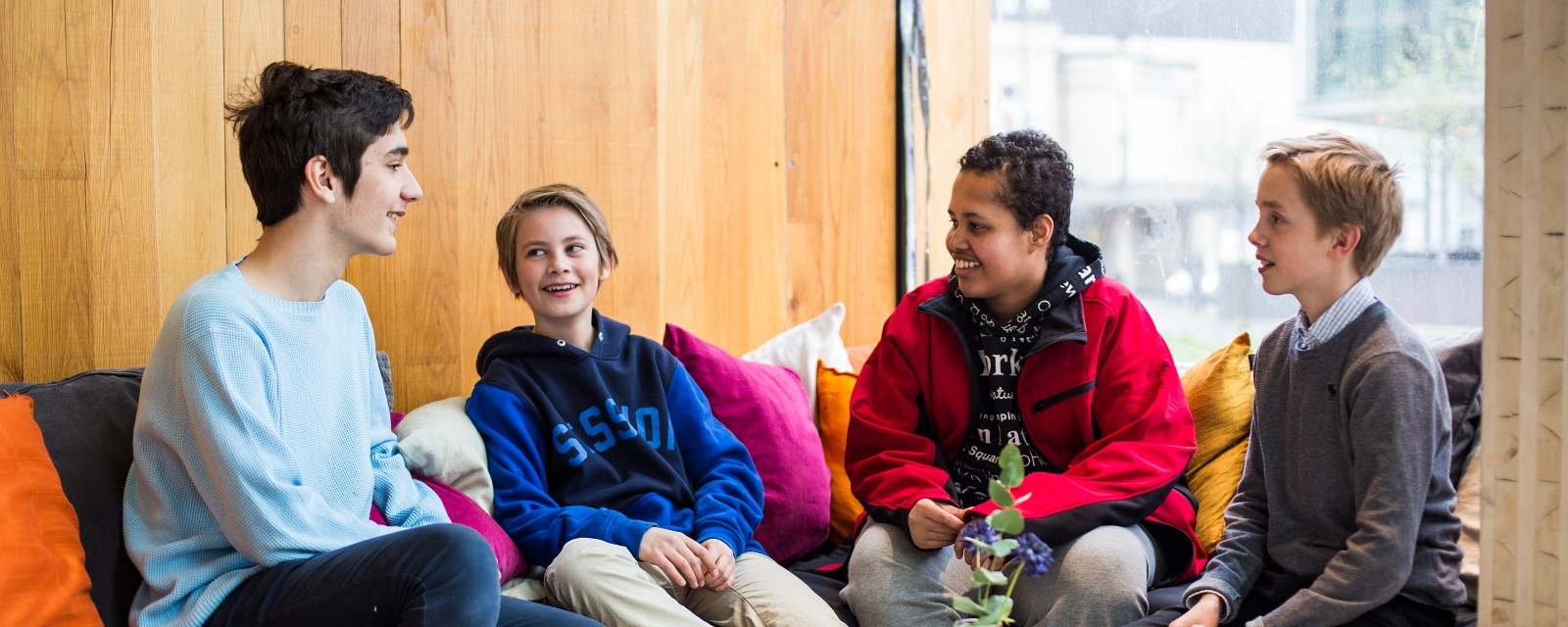 Ungdommer smiler og ler rundt et bord på Cafe Condio