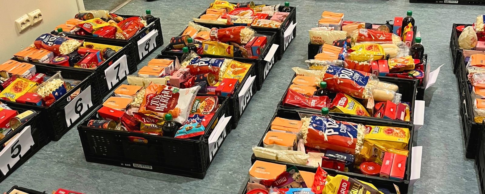 Bildet viser mange fulle matkasser oppstilt på golvet.