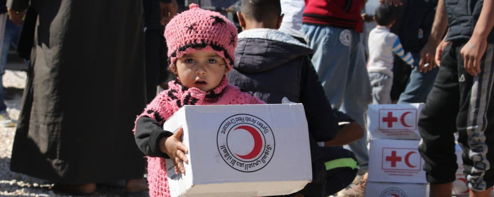 Liten jente holder eske med Syriske Røde Halvmånes logo