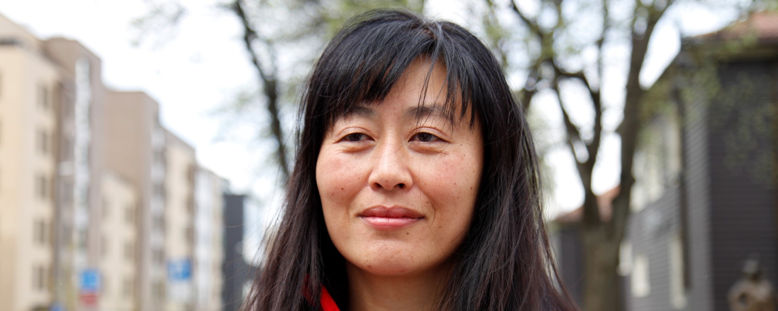 Anja ser ettertenksom ut med trær og bygninger i bakgrunnen, tilbake på stedet hvor hun reddet en mann ved å gi ham hjerte- lungeredning