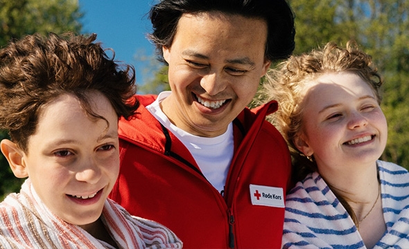 En frivillig ler og smiler med barn ute