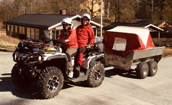 To personer på firehjuling med tilhenger bak.
