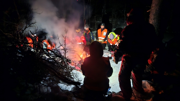Frivillige i hjelpekorpset rundt et bål på vinteren.