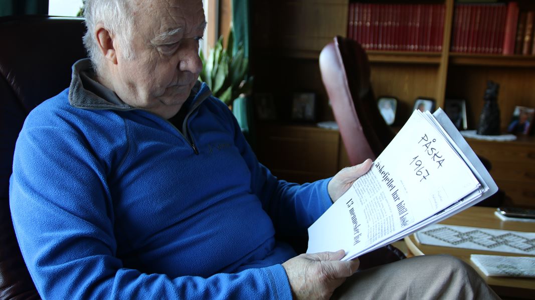 En eldre mann med hvitt hår ser gjennom gamle avisklipp