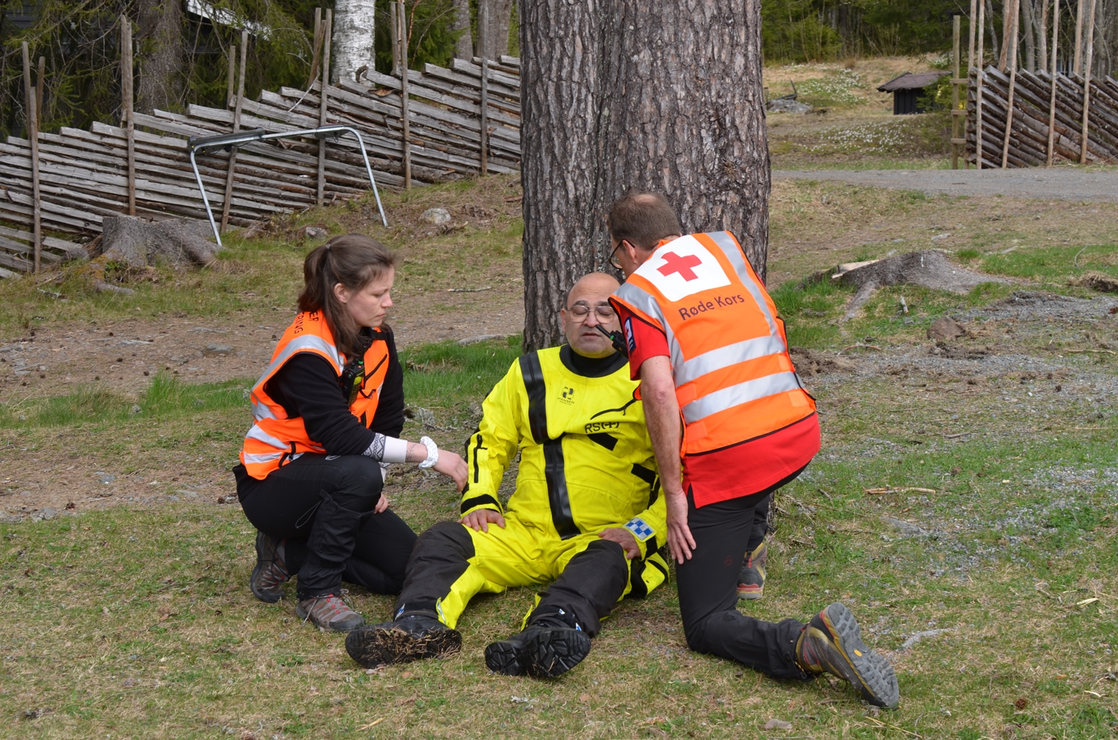 To frivillige og en markør på øvelse i skogen.