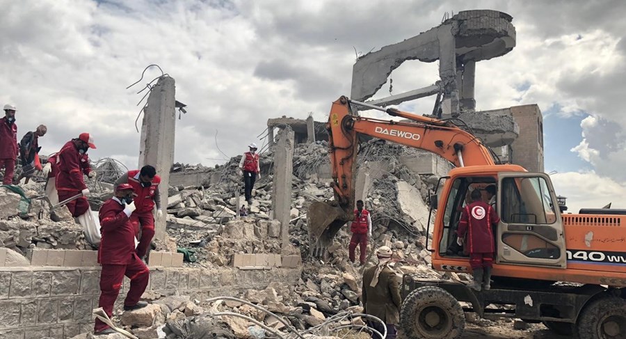 Hjelpearbeidere fra Røde Kors står i ruinene av et fengsel som ble bombet i Syria.