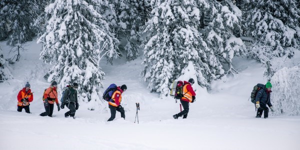 Fire personer med hjelpekorpsuniform går på ski
