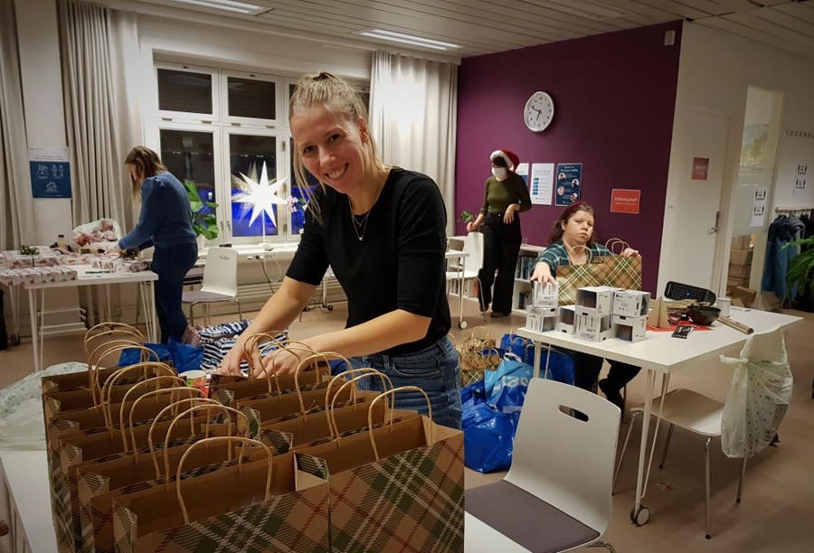 Frivillig jente smiler mot kamera mens hun pakker inn gaver