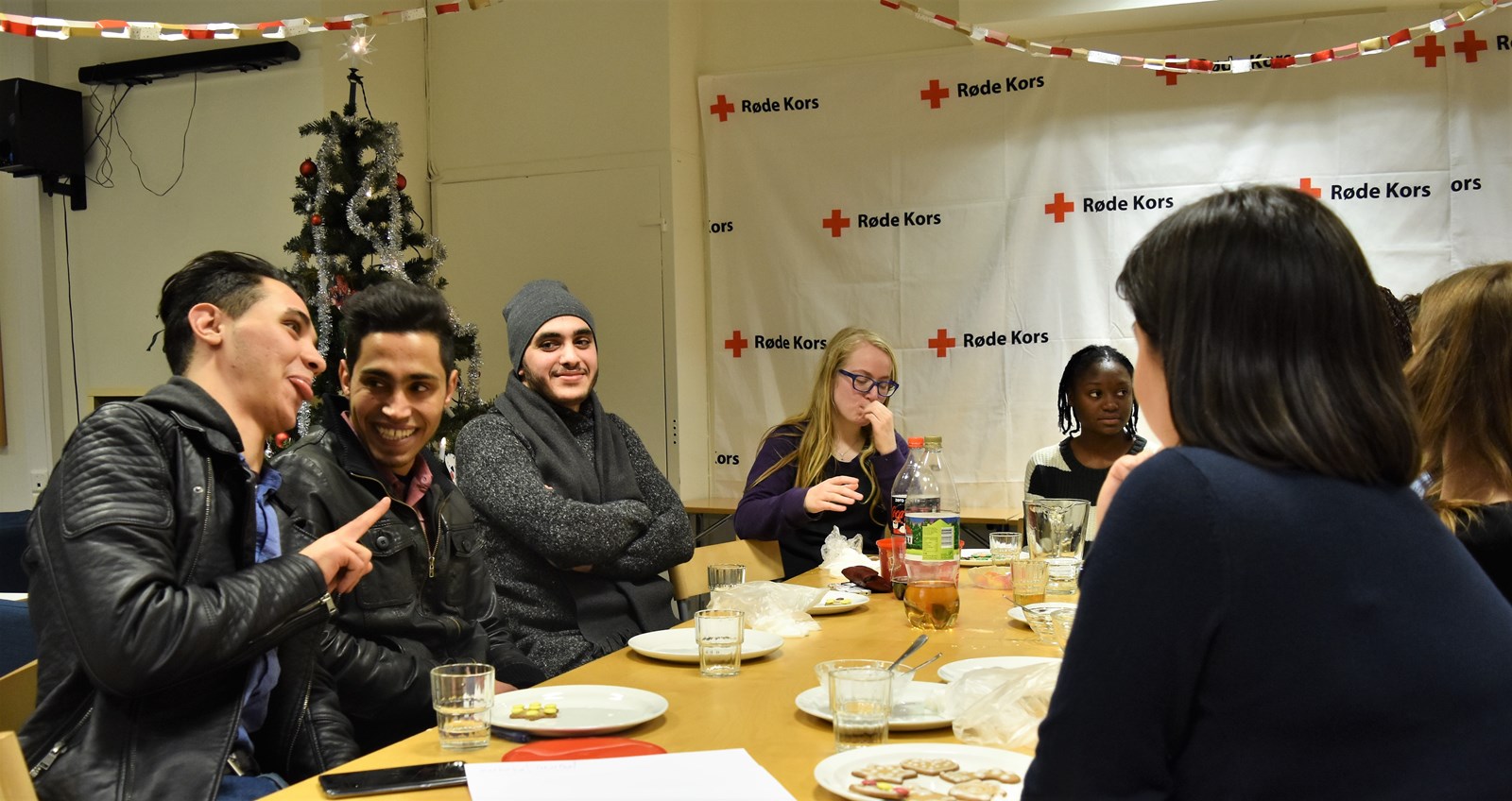 En munter samling ungdommer med flerkulturell bakgrunn rundt lunsjbord til multimix aktiviteten i Røde Kors.