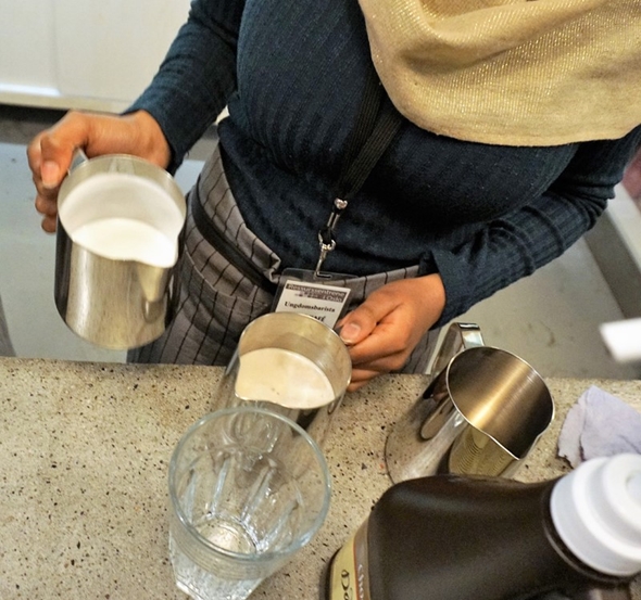 Nærbilde av hender til person med steamet melk