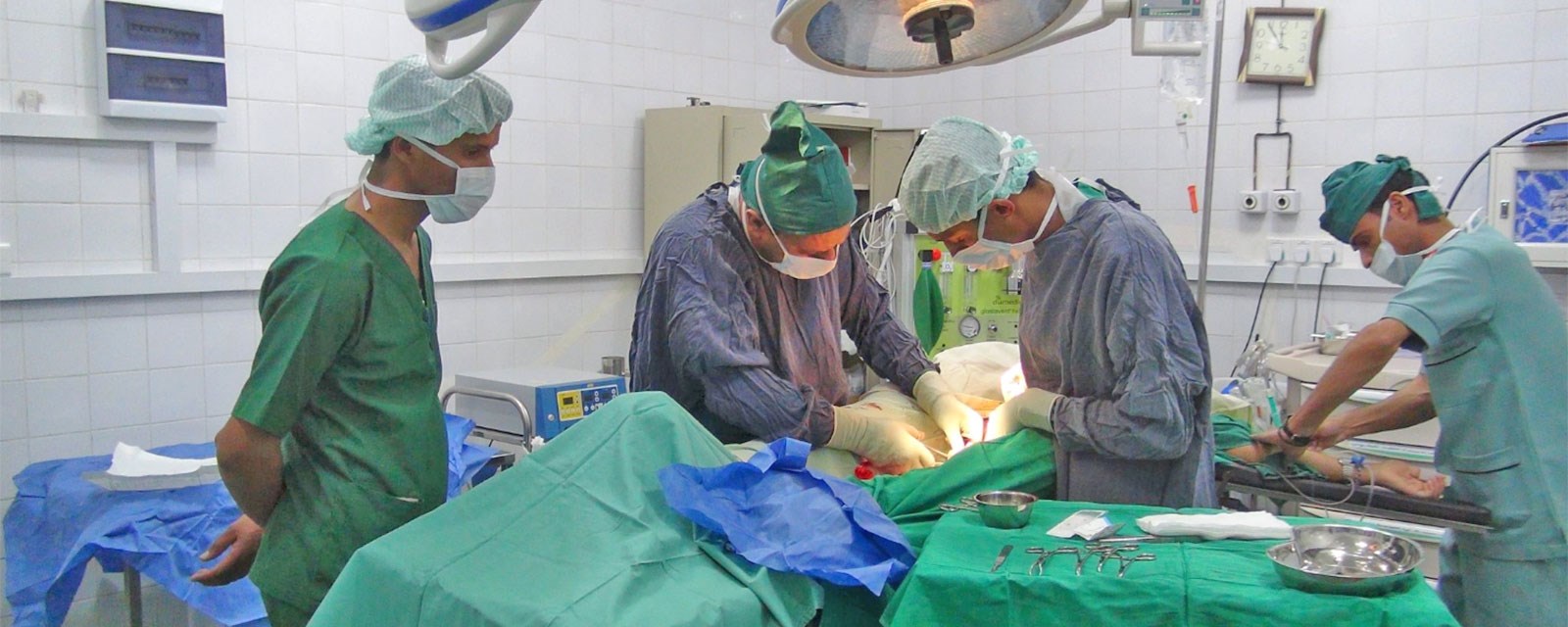 Kirurger står bøyd over en pasient, iført operasjonsklær