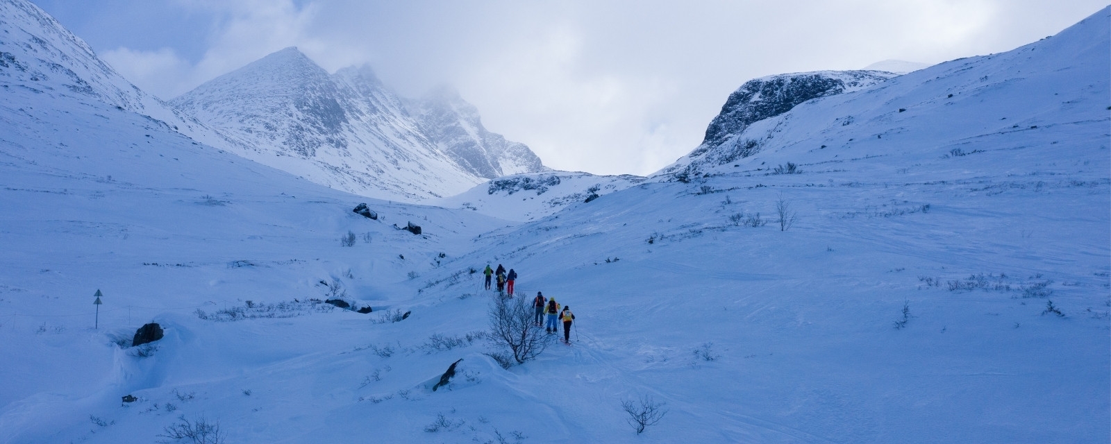 oversiktsbilde av fjellandskap om vinteren på Turtagrø med skigåere på vei opp