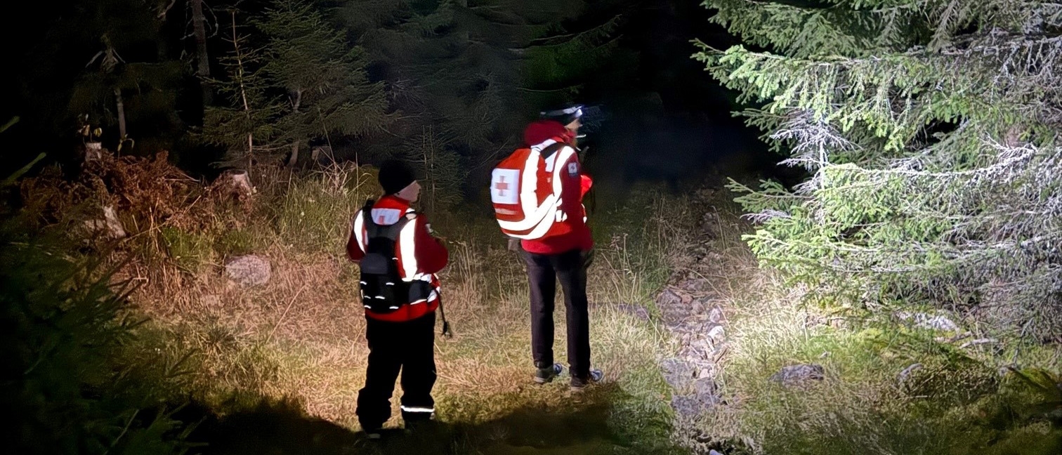To frivillige i hjelpekorpset ute i mørk skogen.