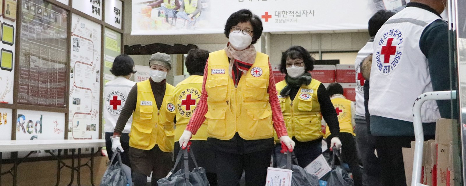 En gruppe mennesker med Røde Kors-vester som bærer varer
