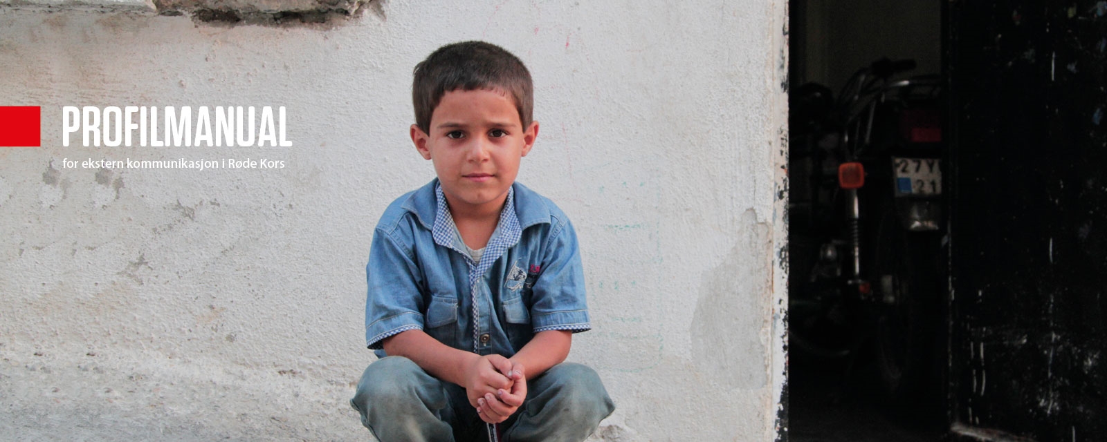 En liten gutt sitter på huk. På siden står teksten: Profilmanual for ekstern kommunikasjon i Røde Kors
