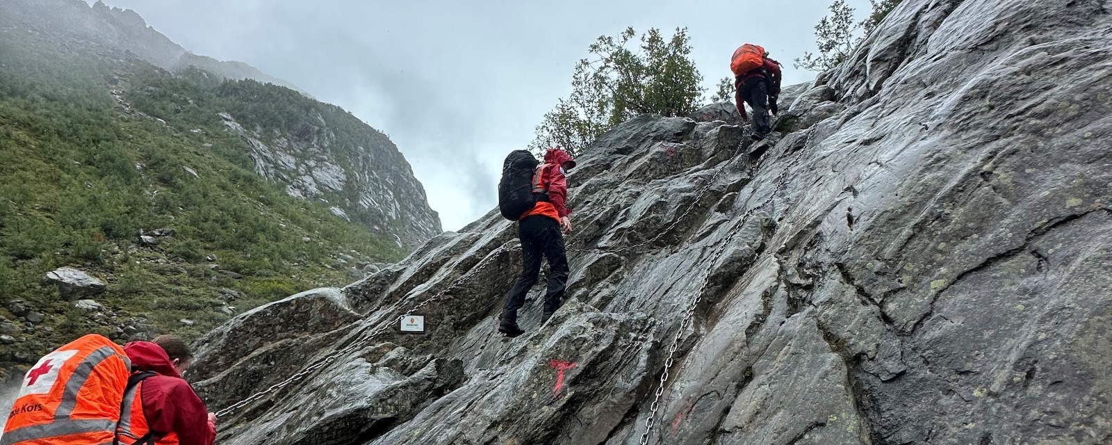 hjelpekorps klatrer opp bratt fjellvegg