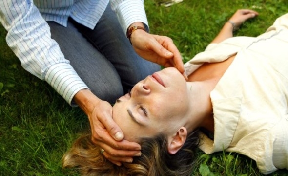 En kvinne bøyer seg over en annen kvinne som ligger bevisstløs på bakken.