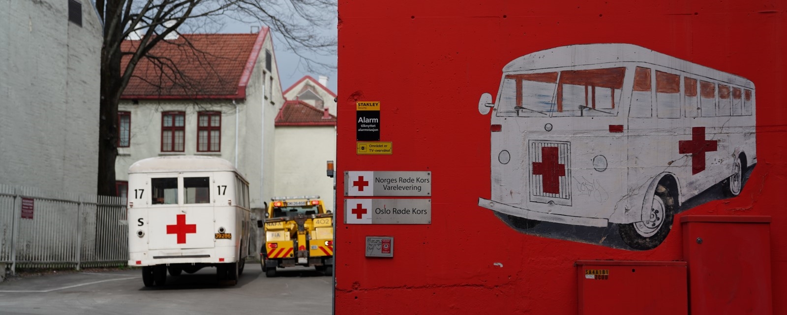 En gammel hvit buss med et rødt kors malt på baksiden