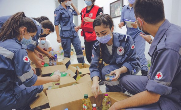Frivillige fra Røde Kors sorterer mat i esker for utdeling