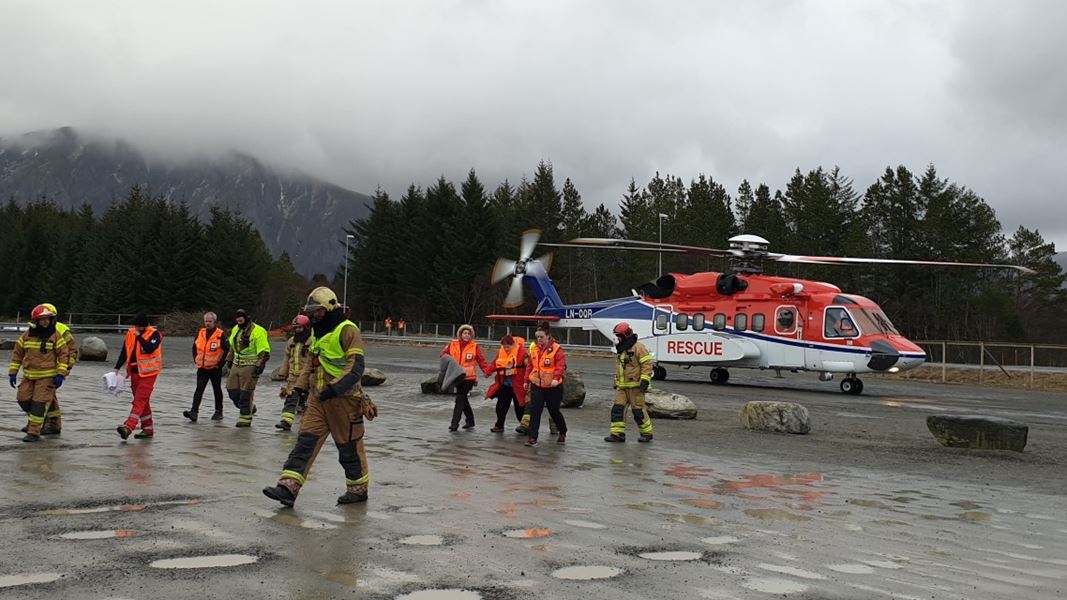 Helikopter ankommer med skadde passasjerer, hjelpemannskaper hjelper til