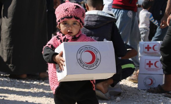 Liten jente bærer eske fra Syriske Røde Halvmåne