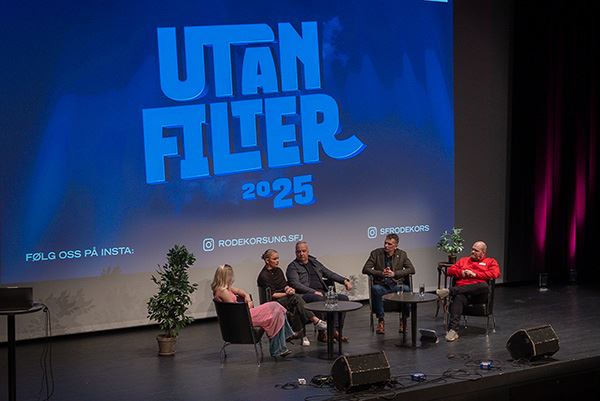 Ein gjeng folk sit på ei scene. Bak dei står det "Utan Filter"