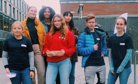 Ungdomsgruppa til Røde Kors foran trekanten storsenter med Røde Kors T-skjorter på. 