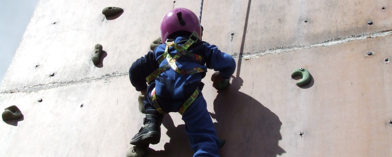 Et barn i klatreveggen med hjelm på hodet 