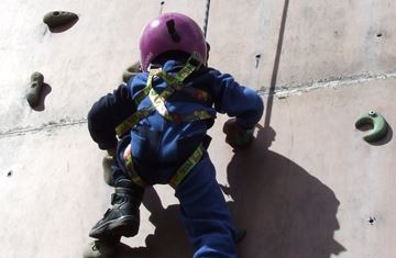 Et barn i klatreveggen med hjelm på hodet 