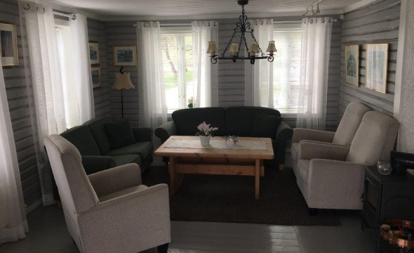 Stuen på Solvik med møbler som bord sofaer og vinduer.