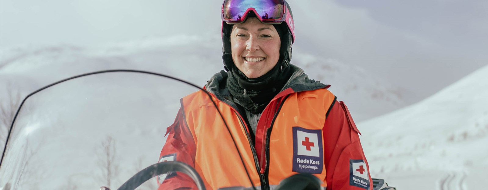 Une dame, Gøril Urdal, på snøscooter smiler til kamera.