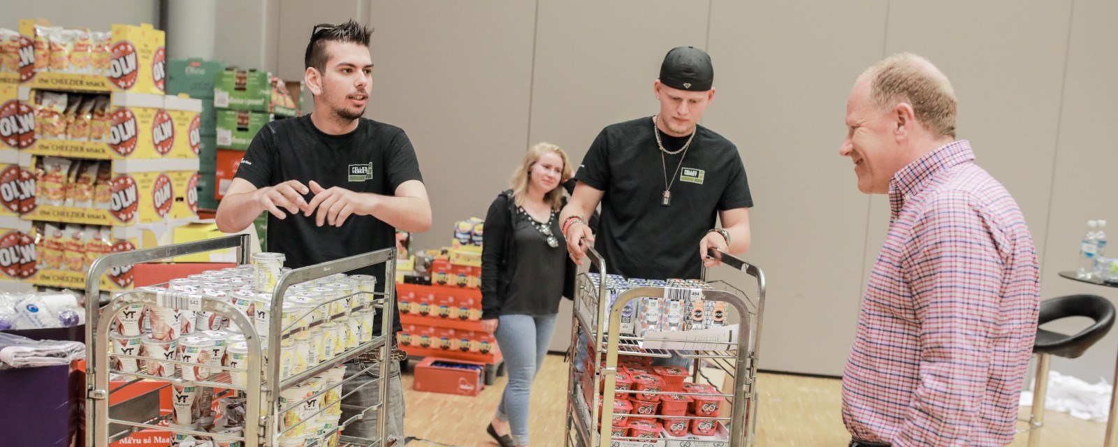 Bildet viser to unge Røde Kors-frivillige som triller med seg matvarer som de har fått av butikkjeden Coop Prix