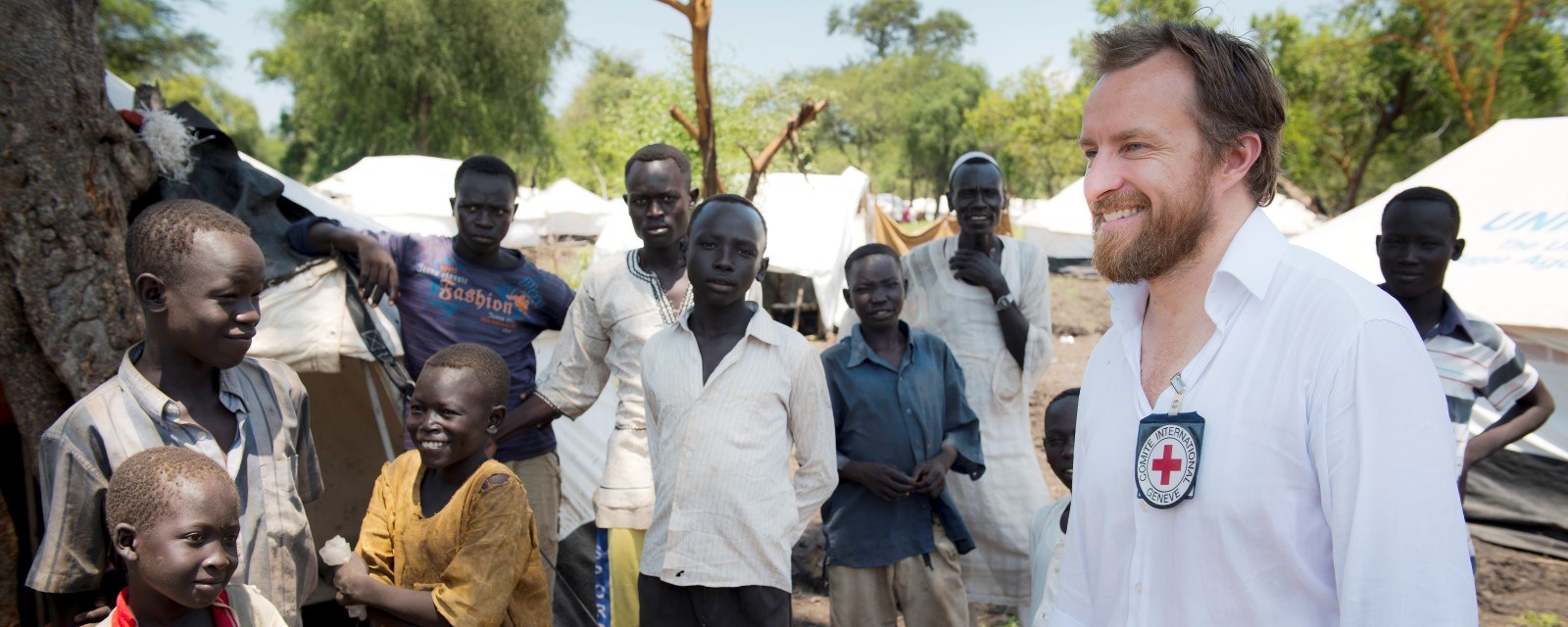 En europeisk mann med skjegg står sammen med 10 unge og eldre afrikanske menn