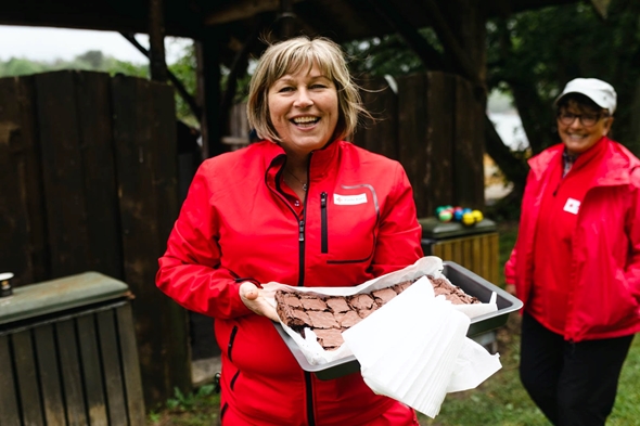 Kvinner i Røde Kors klede serverar kake.