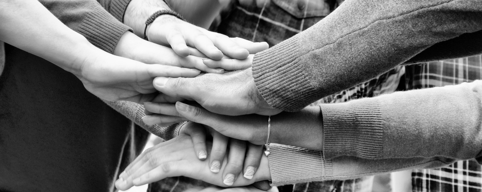 Mange forskjellige hender oppå hverandre, viser samhold