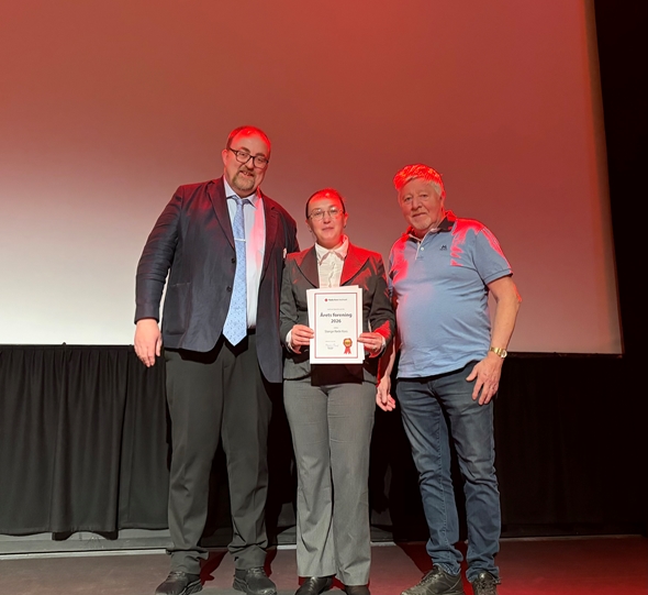 Tre personer på scenen med en utmerkelse.