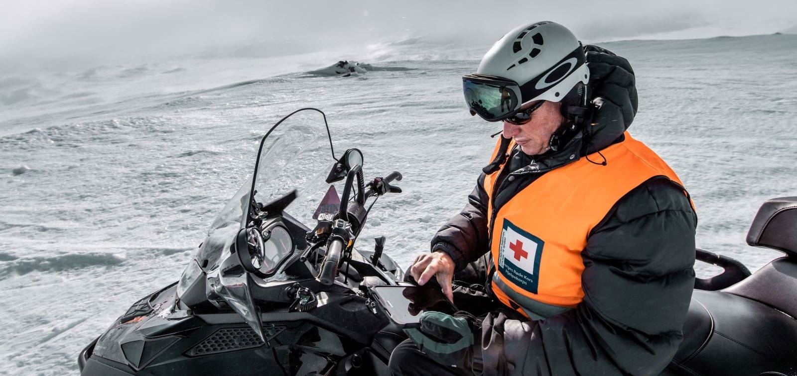 Hjelpekorpser på fjellvidden med tablet og snøscooter