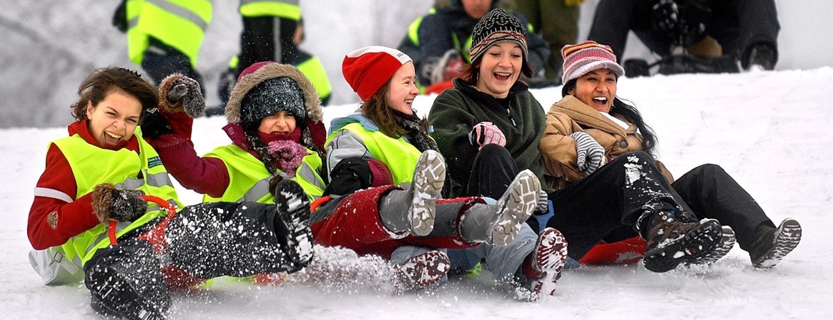 barn i gule vester som aker i snøen