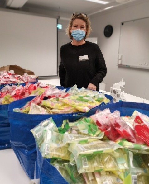 Dame med munnbind og store blå IKEA-poser fulle med godteri