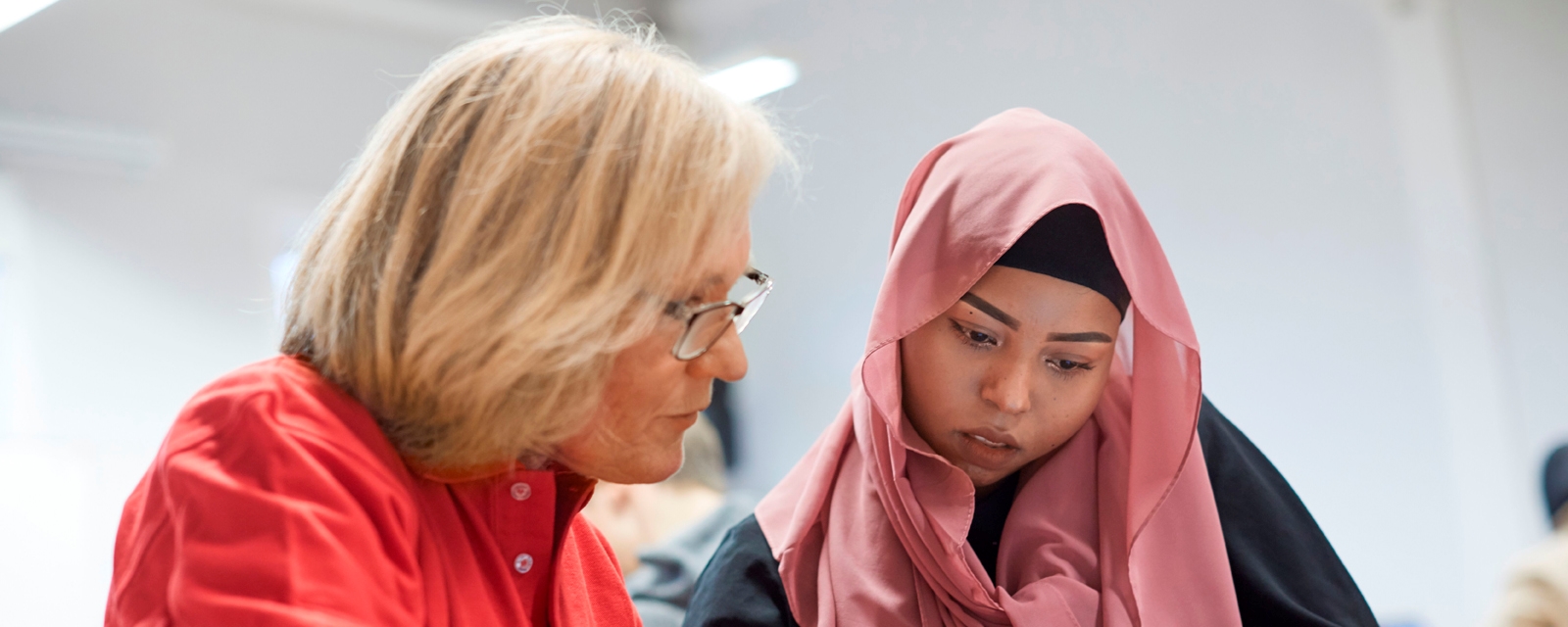 En voksen leksehjelper, kvinne hjelper en ung kvinne med lekser